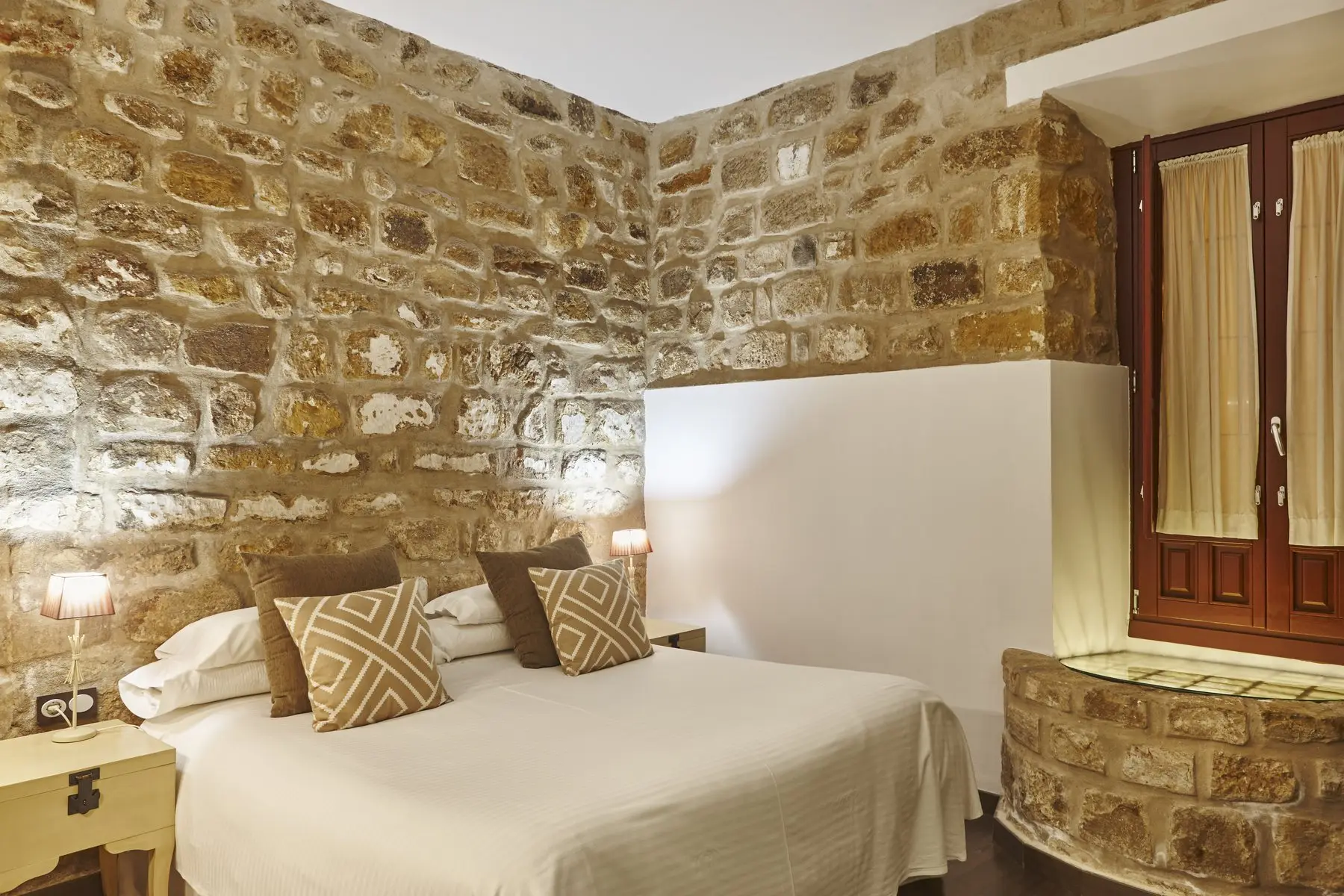 Chambre d’hôtes aux murs de pierre apparente, lit fait et décoration sobre