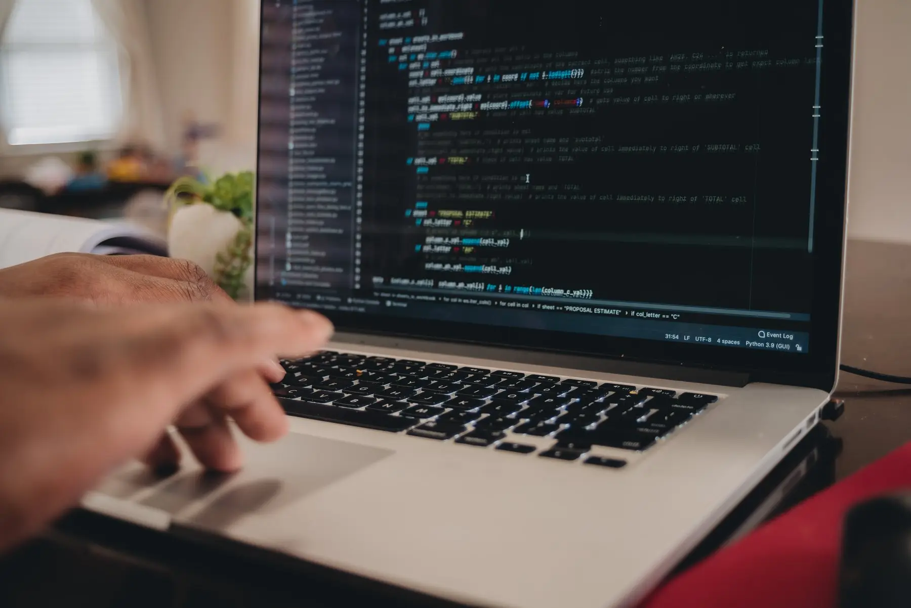 Des mains sur le clavier d’un ordinateur portable dont l’écran affiche des lignes de code