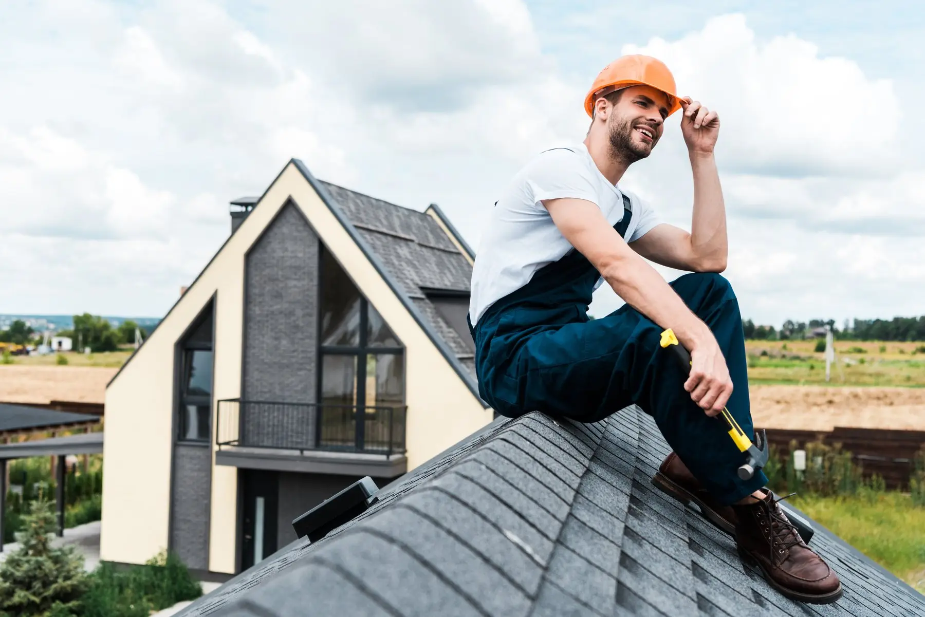 Un couvreur assis sur le toit d’une maison neuve en construction