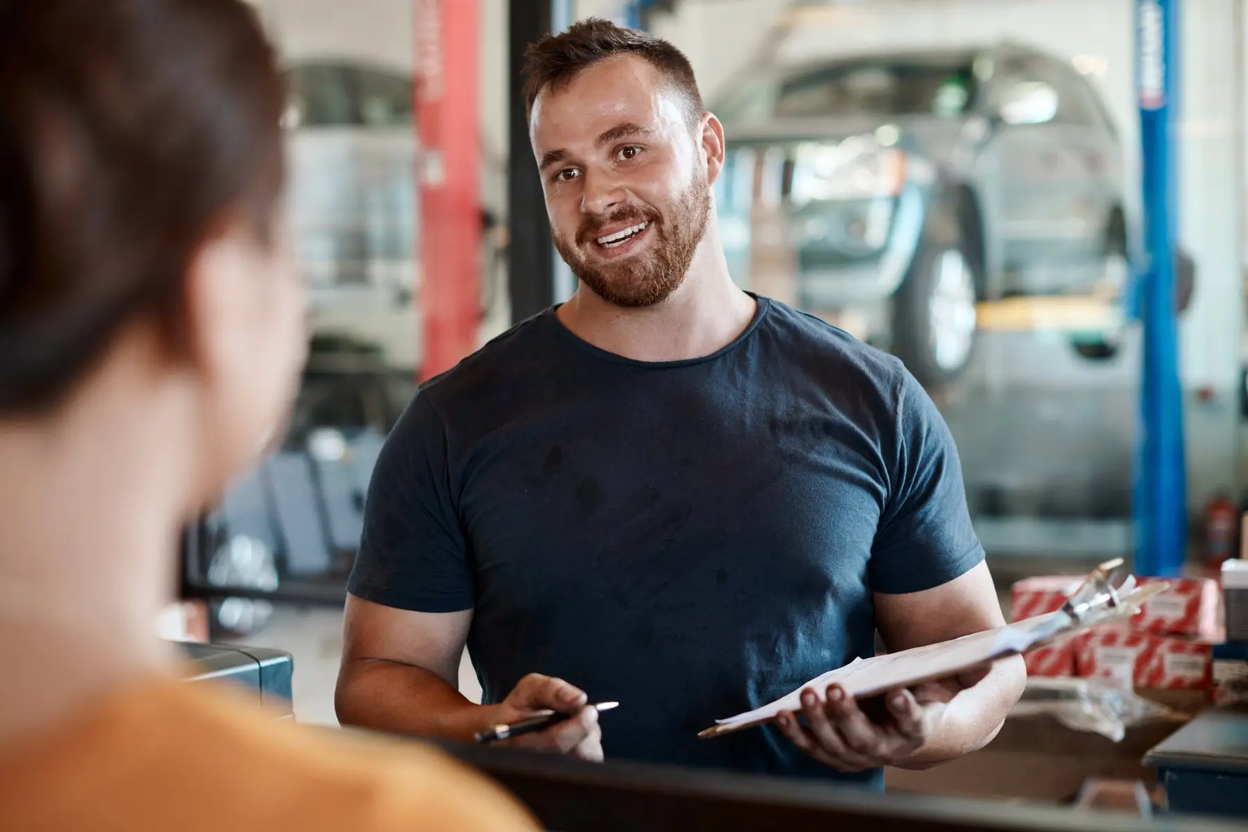 Un mécanicien explique une intervention à une cliente à l’accueil d’un garage