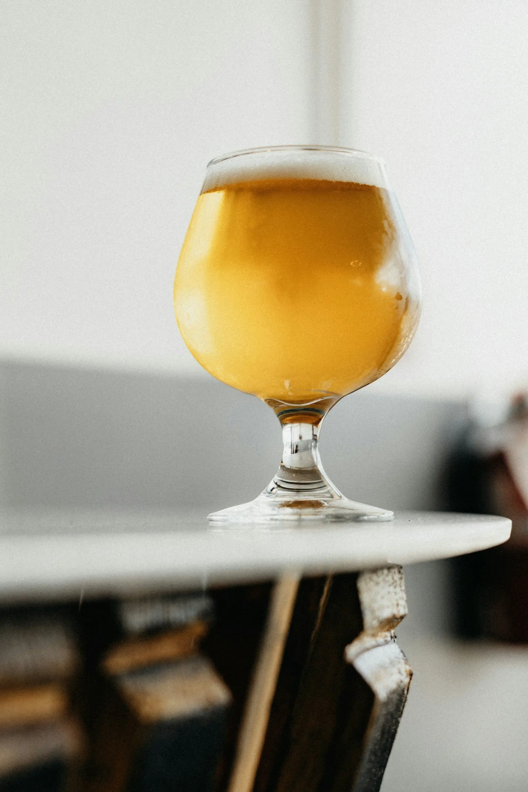 Un verre à pied rempli d’une boisson dorée et pétillante, posé au bord d’une table