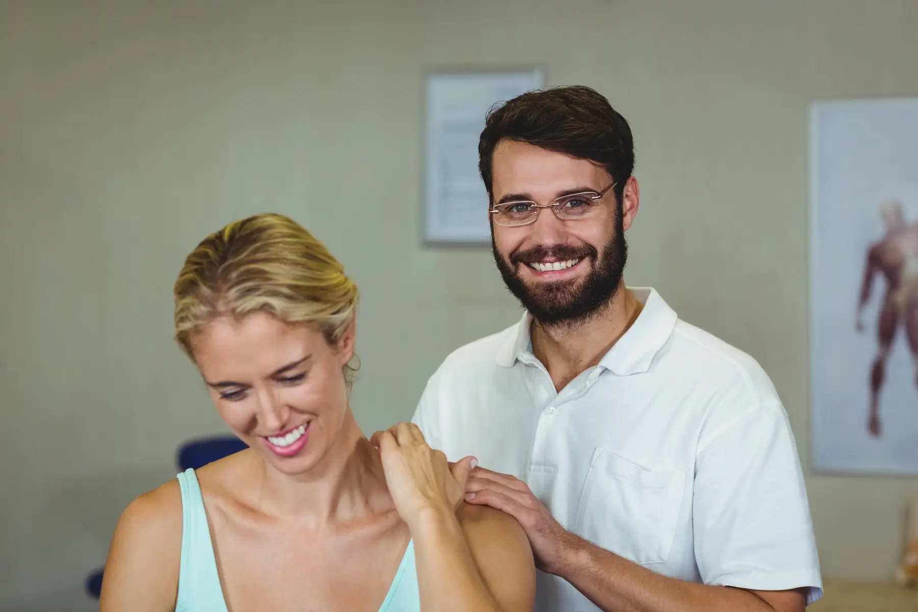 Un praticien souriant pose la main sur l’épaule d’une patiente souriante, dans une salle de consultation