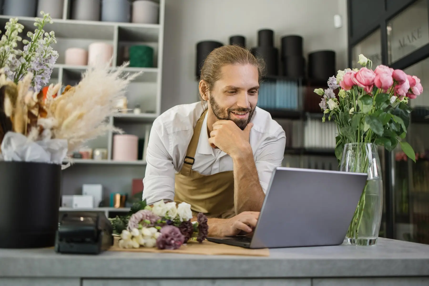 Un fleuriste met à jour son site internet sur un ordinateur portable, dans sa boutique