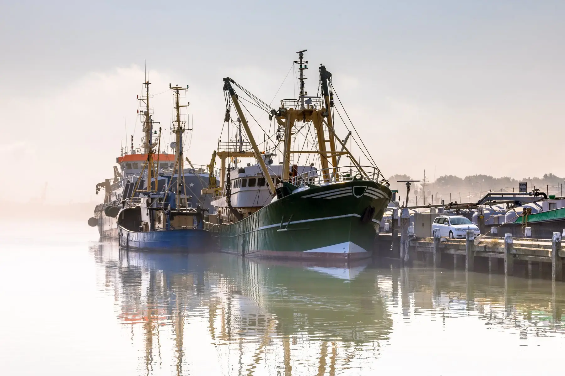 Des bateaux de pêche à quai au petit matin, sur une eau calme