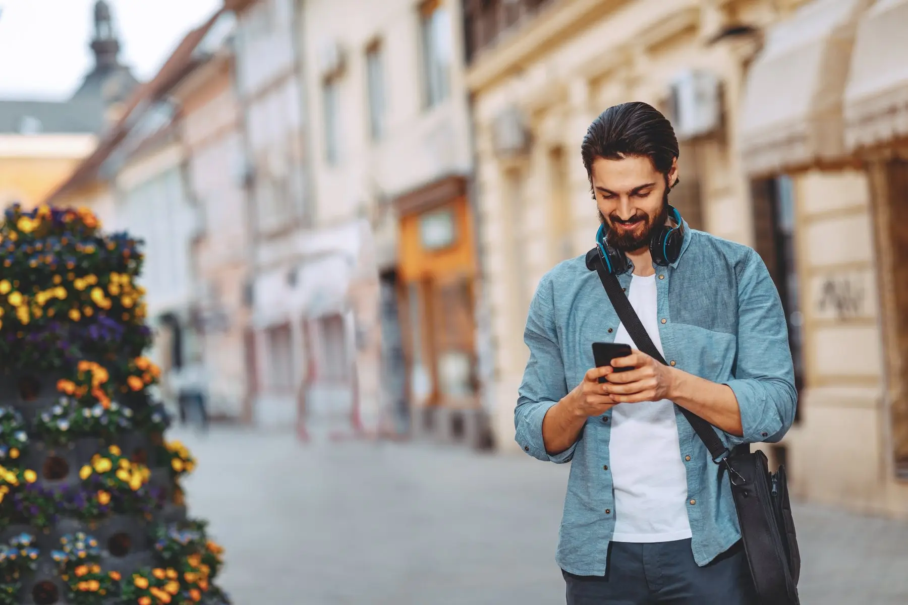 Un homme consulte son smartphone dans une rue commerçante pour trouver une adresse à proximité