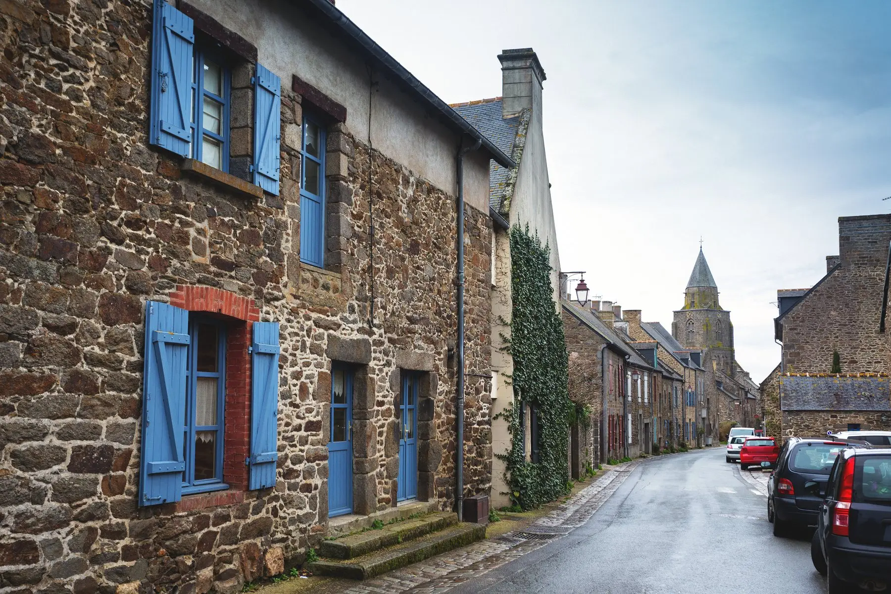 Une rue de village breton bordée de maisons en pierre aux volets bleus
