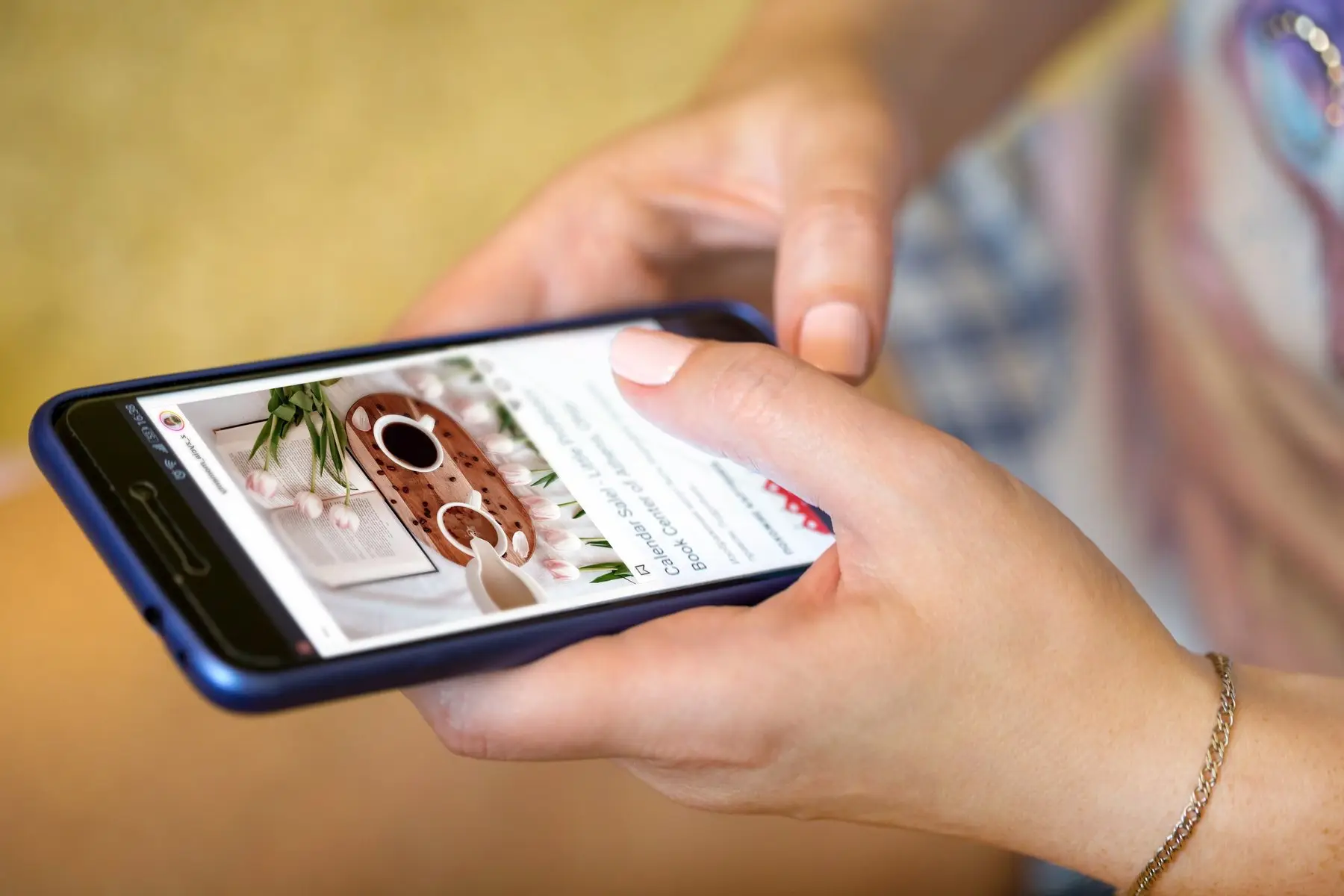 Une main tient un smartphone qui affiche un site internet