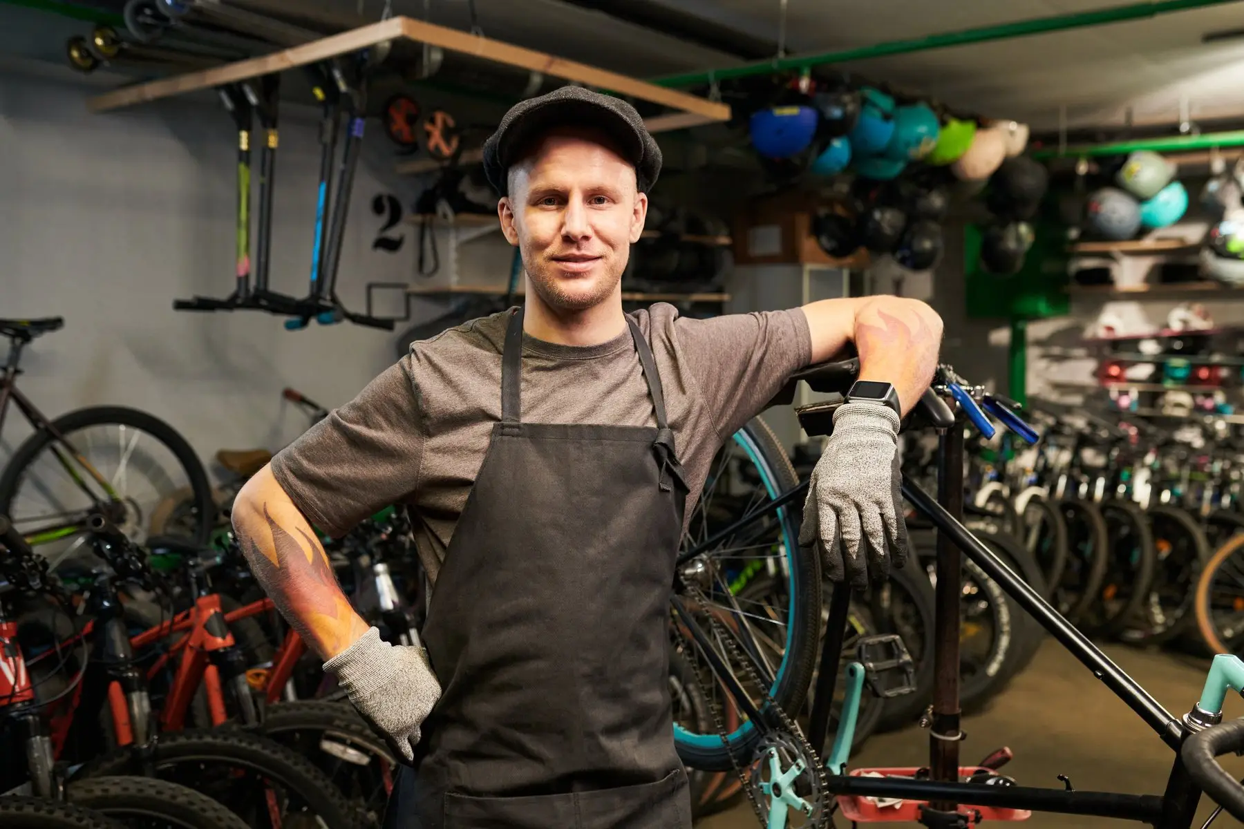 Un réparateur de vélos en tablier pose dans son atelier, au milieu des cycles alignés